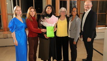 Rita   in yellow receiving her award listing
